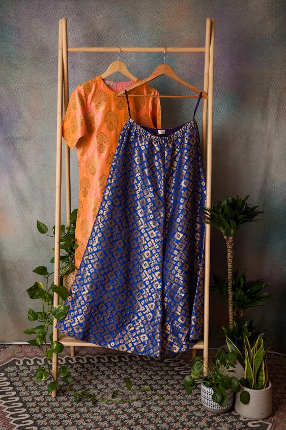 blue and gold brocade flared trousers, accompanied with a pearlescent orange top, with a gold floral subtle embroidery. 
